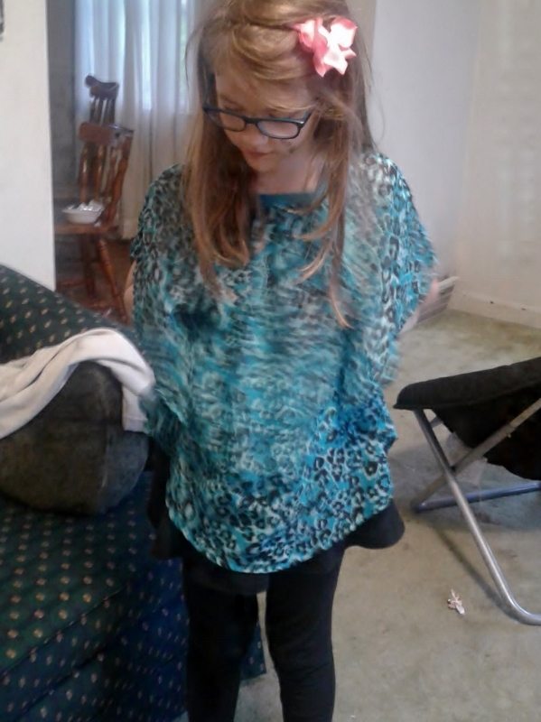 Girl in blue leopard print flowy sheer shirt, black skirt/leggings, and pink flower on a headband