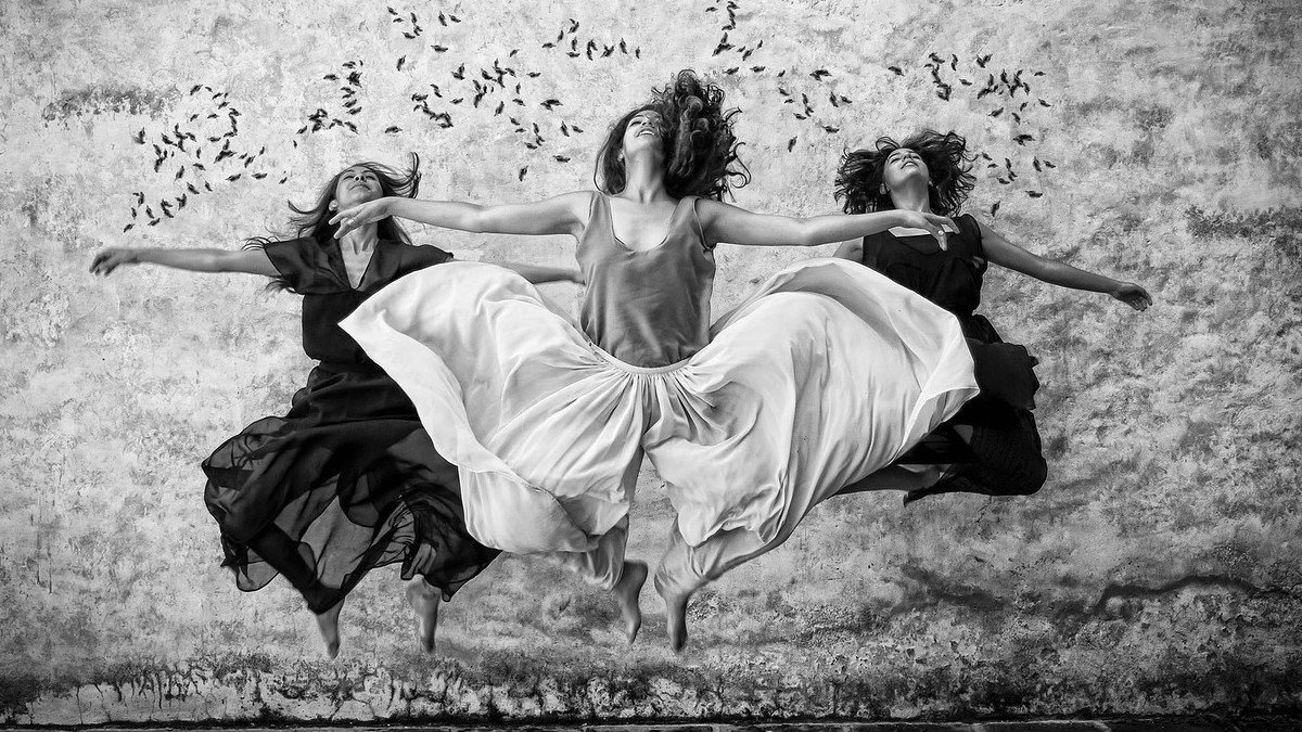 three women jumping in a row, their skirts floating around them