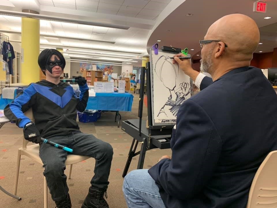 Caricaturist draws a cosplayer dressed as Nightwing 